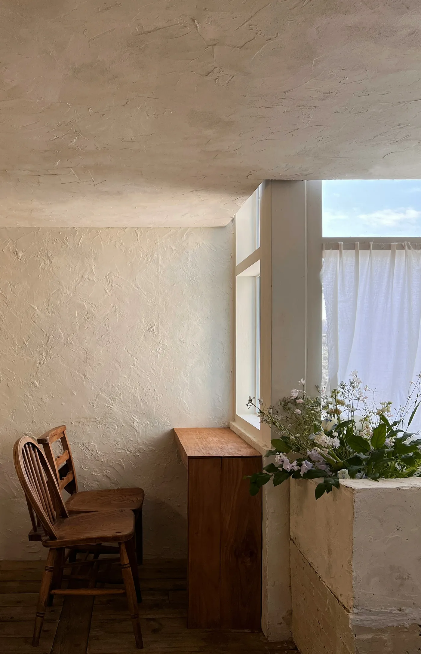Wooden chair beside a bright window in a neutral interior